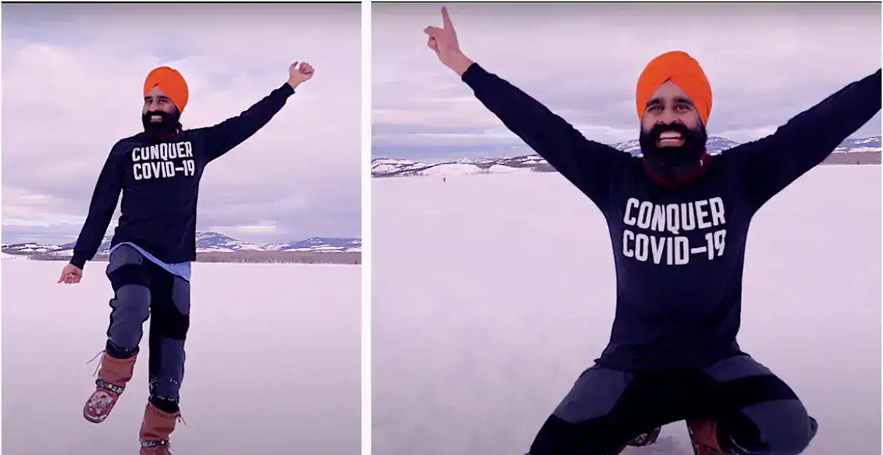man taking selfie in orange turban and black outfit to celebrate covid 19 vaccination with a black shirt that reads Conquer Covid-19